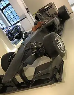 A black Formula One car displayed in a museum.
