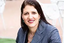 close-up of Talya Miron-Shatz wearing a blue jacket, grinning directly at camera