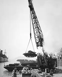 A crane hoisting a tank into a boat