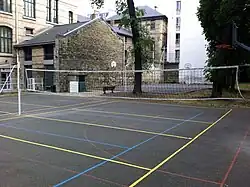 Photograph of the sports fields at Lycée Molière, with one of the lycée's façades and annex buildings in the background.