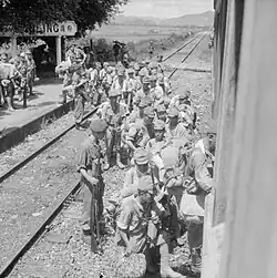 Surrendered Japanese troops board a train at Fanling station under the watch of British forces.