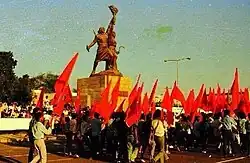 People celebrating the victory of the 14th October Revolution in South Yemen by waving red flags next to the Freedom Statue