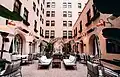 Courtyard dining area surrounded by pink stucco walls with windows