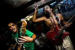 Two men performing while holding Guitars