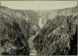 A black and white photograph of a valley and river, the Teton Range in the background