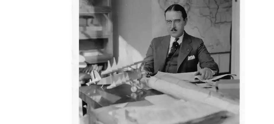 Thomas Carroll at his desk with models of biplane aircraft