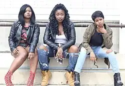 Image 31Three women wearing grunge and streetwear inspired outfits with elements such as distressed jeans, combat boots, tied flannel, and bold lipstick, 2015. (from 2010s in fashion)