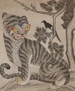 A vertical painting in watercolor on paper with primarily black, white, and gray tones. It depicts a stylized tiger with a humorous, exaggerated expression and yellow eyes sitting at the bottom and looking up toward a magpie perched on the branch of a gnarled pine tree above.