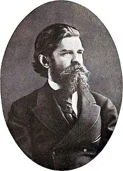 Black-and-white photograph of a bearded adult man in a suit