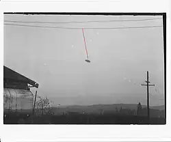Black-and-white photo of a disc-shaped object connected to a cable by a hypothetical red thread.