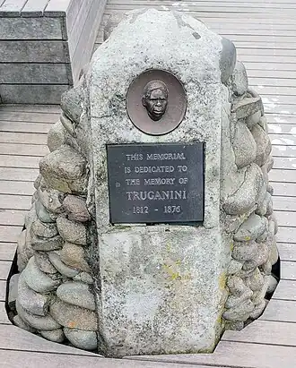 Stone memorial with an inset bronze face and a plaque reading, "This memorial is dedicated to the memory of Truganini 1812–1876".