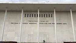 Exterior sign showing Donald Trump's name in addition to John F. Kennedy's name on the side of a white building