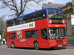 Red double-decker bus with blue-painted top deck and white logos of outline of the British Isles defaced with the text 'U.K. North of Manchester'
