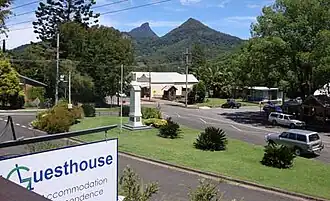 ANZAC Memorial and village. Historic "Sweetnam's Humpy" is visible in the mid-distance and Mt Warning is visible in the background.