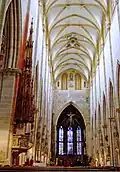View toward the choir showing the ancient glass in the apse and the wooden filigree canopy of the nave pulpit