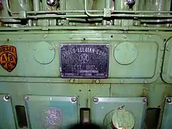 A green diesel engine with a plaque saying ANGLO-BELGIAN-CORP. It has a logo with three engine pistons and the letters A, B and C