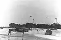 LST-344, (left) and LST-338 (right) unloading troops and supplies on the Gela invasion beaches in Sicily on "D-Day" 10 July 1943. Broached LCVP at right is from the Barnett&nbsp;(APA-5); the next LCVP to the left is from the Monrovia&nbsp;(APA-31).