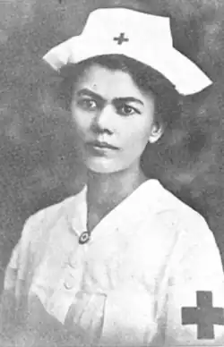 A woman with olive skin, dark hair and eyes, wearing a nurse's uniform