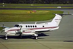 A small aircraft with two propeller engines and six cabin windows on the ground