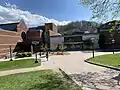 This image depicts the Varsity Gymnasium from the opposite side of the previous image, showing the building from the perspective of a viewer standing next to Anne Belk Hall. The Roess Dining Hall can be seen to the side of the gym