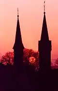 Moonset in May. In foreground at left the Catholic church, at right the Evangelical church, view towards the west