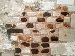 Color photograph of a wall with stones forming geometric patterns.