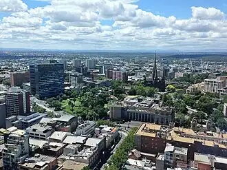 Looking toward Eastern Hill (East Melbourne's northern end) from the Melbourne central business district. Visible landmarks (from left to right) include ICI House, East Melbourne Hebrew Congregation, Eastern Hill Fire Station, Parliament House, St Peter's Church, Eastern Hill, Victorian Artists Society buildings, St Patrick's Cathedral, Former St Patrick's College tower, Tasma Terrace as well as Spring Street and Parliament Place tram routes.