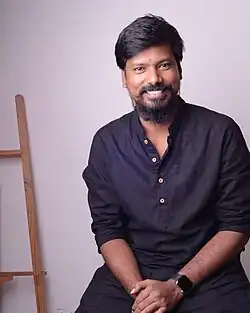 Photograph of Indian filmmaker P. S. Vinothraj seated and smiling, wearing a black shirt.