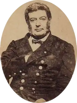 Photographic portrait of a dark-haired man with sideburns, dressed in a double-breasted military tunic with his right hand tucked under the lapel of his jacket