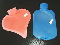 Two modern hot water bottles shown with their stoppers