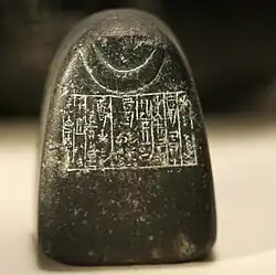 Weight of +1⁄2 mina (actual weight 248 gr.) dedicated by King Shulgi and bearing the emblem of the crescent moon: it was used in the temple of the Moon-God at Ur. Diorite, beginning of the 21st century BC (Ur III). Louvre Museum, Department of Oriental Antiquities, Richelieu, first floor, room 2, case 6.