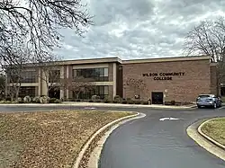 A two-story brick building with the name of the college in black letters on the side