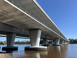 A long concrete bridge crossing a river viewed from below