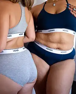 Two women wearing "Woxer" brand high-cut briefs and sport bras