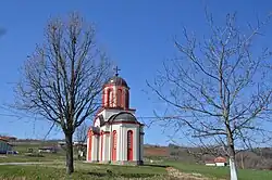 An orange and white striped small church in a field