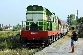 A class T669 diesel locomotive pulls a passenger train arriving at Lac station, Albania, in 2012