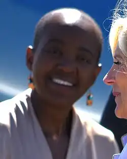 Headshot of Williams smiling against a blue background, with Jill Biden emerging from the right