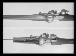 Two Kalthoff repeating guns viewed from above, one missing its barrel and breech cap, exposing the ball magazine.
