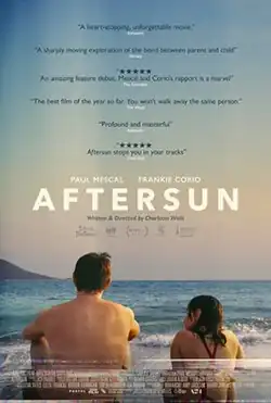 In grainy footage reminiscent of an early camcorder, a man and a young girl sit at the beach looking towards the horizon. The girl glances over at him. The word "aftersun" is placed above them in big letters. Below them, the image fades out in glitchy effects.