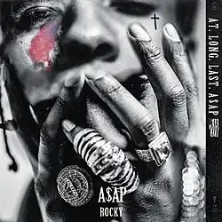 A black-and-white image of ASAP Rocky covering his face with his hands, which are adorned with rings. His hands hold up the face of the late ASAP Yams, whose distinctive birthmark is colored in red and purple.