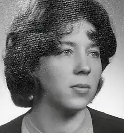 Black and white, three-quarter profile, studio portrait of a young, dark-haired, unsmiling woman with late 1950s or early 1960s short and permed hairstyle, and light makeup.