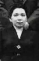 A Black woman with light skin and dark hair, wearing a dark suit