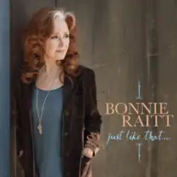 photo of Bonnie Raitt in brown jacket with blue shirt looking away