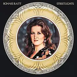 color portrait photo of Bonnie Raitt in wide metal circular frame on black background