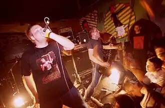 A promotional image of Botch performing live with work lamps aimed at the audience. Vocalist Dave Verellen is on the left, guitarist Dave Knudson is on the right.