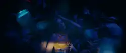 Dua Lipa dancing in a crowded nightclub.