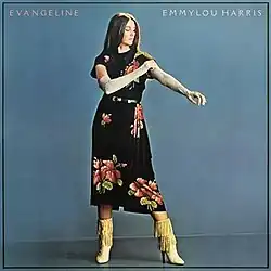 photo of Emmylou Harris in flower print dress with high-heeled western boots adjusting a lace sleeve