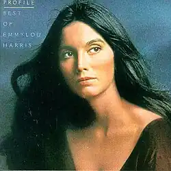 head and shoulders portrait of Emmylou Harris in dark red glancing to the side