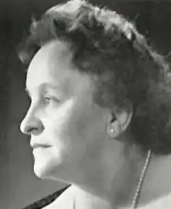 Vintage black and white profile publicity shot of an unsmiling woman with short, curly hair