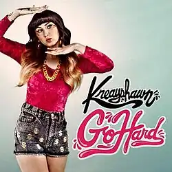 A woman with ombré hair in a red shirt and high-waisted black shorts voguing. The text "Kreayshawn Go Hard" stands to her left.